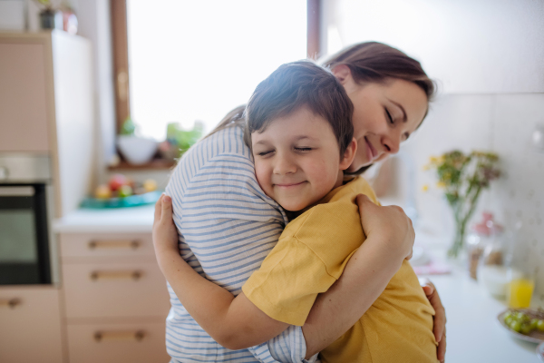 A happy oung mother hugging her little son in kitchen at home.