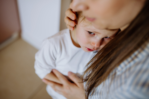 A mother consoling her little upset daughter at home.