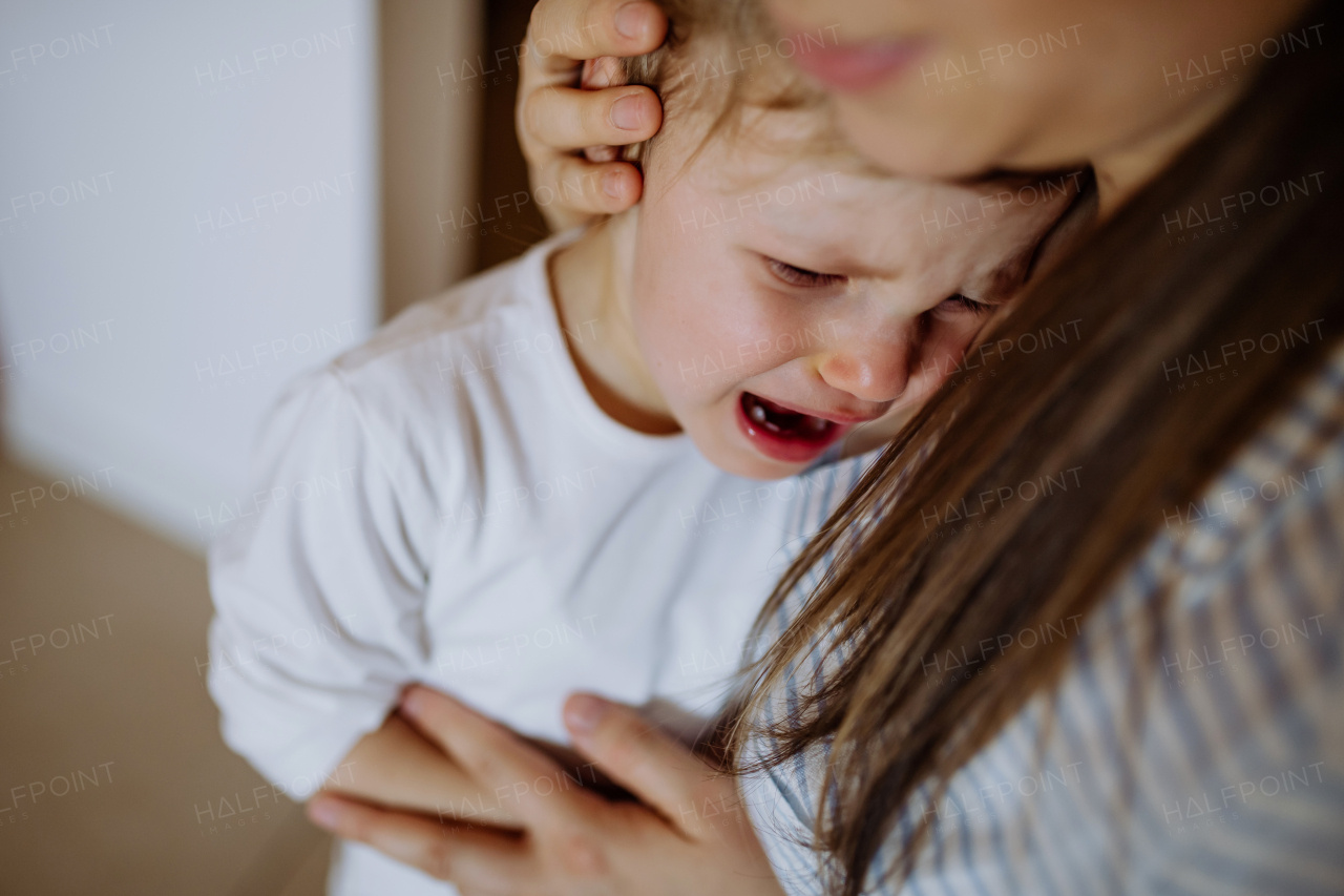 A mother consoling her little upset daughter at home.