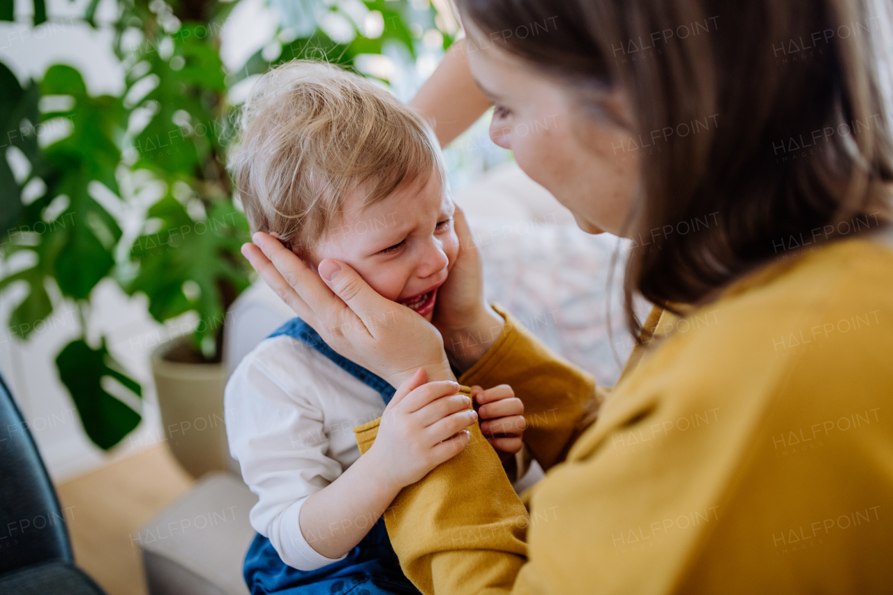 A mother consoling her little upset daughter at home.