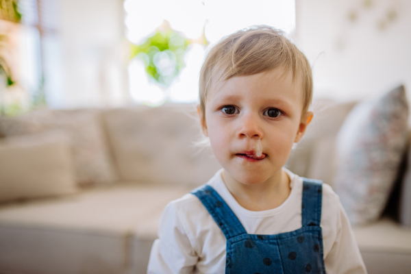 A portrait of sad little girl with snot running through her nose, looking at camera.