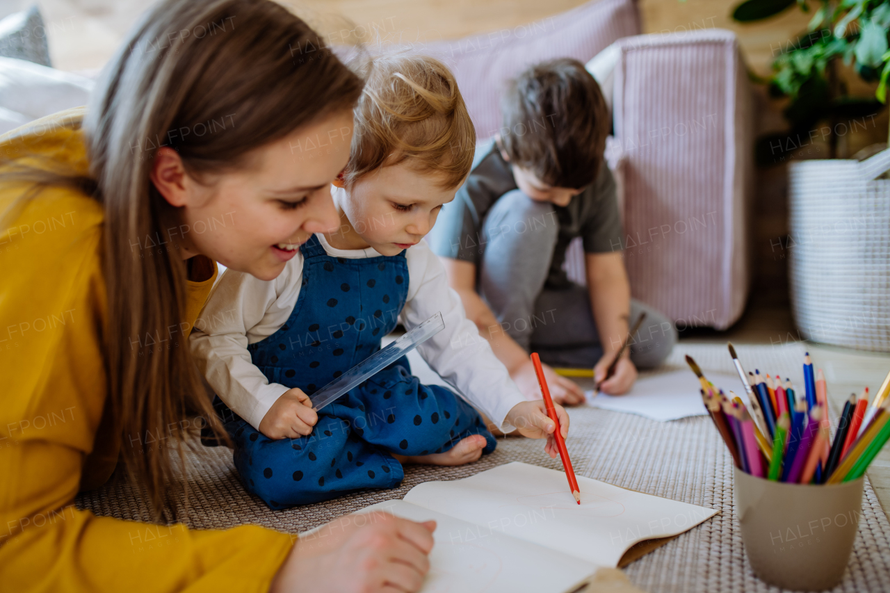 A mother with her little children at home drawing together.