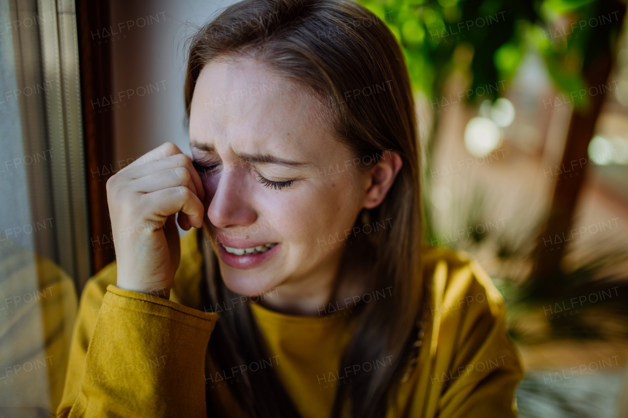 A woman suffering from depression and crying at home.