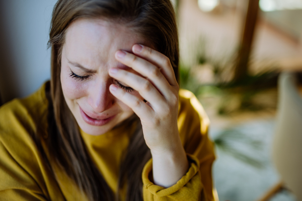 A woman suffering from depression and crying at home.