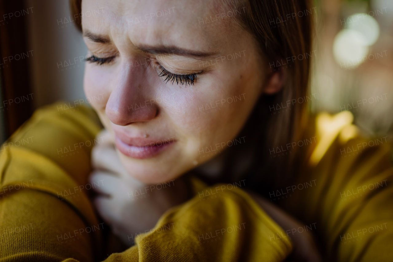 A woman suffering from depression and crying at home.