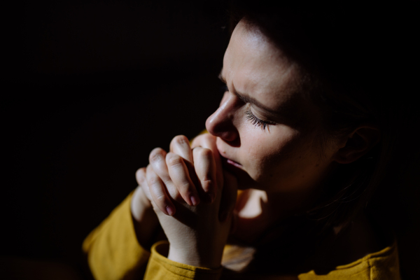 A sad woman holding hand blessings and pray, feeling down, begging for help. Spirituality,religion concepton on black background.