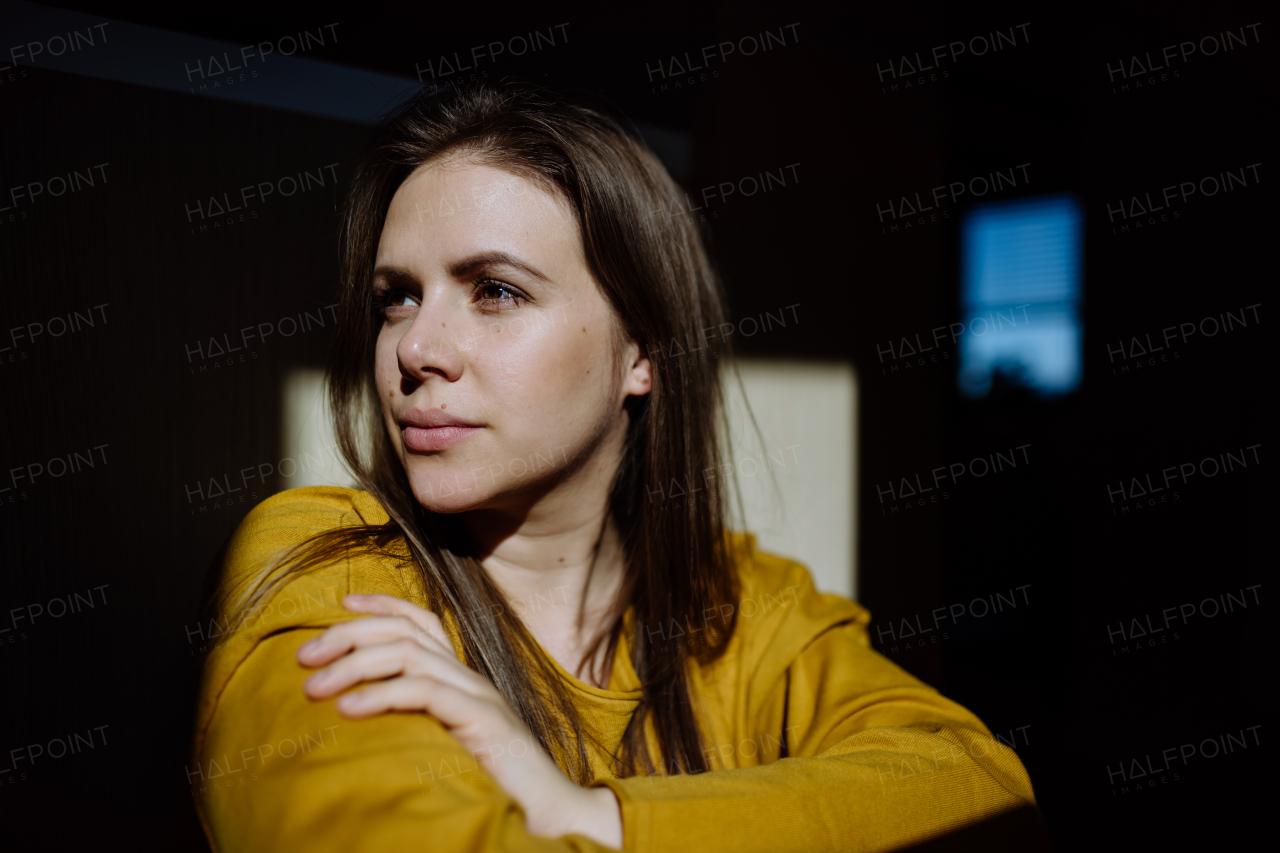 A close-up portrait of young woman resting at home, shot through window.