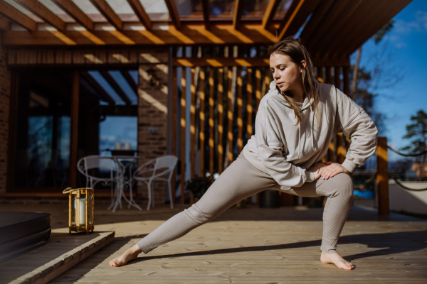 A young woman exercising and stretching outside on terrace at home.