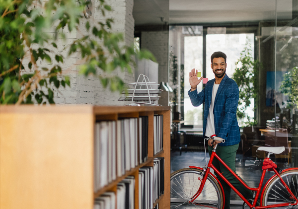 Young multiracial man with bicyckle in an office.