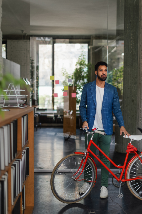 Young multiracial man with bicyckle in an office.