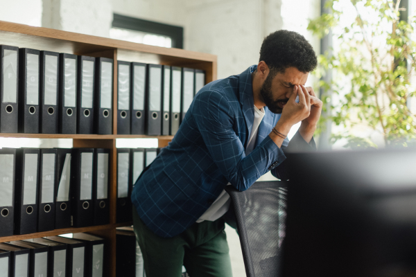 Young frustrated, exhausted businessman in his office. Signs of burnout at work.