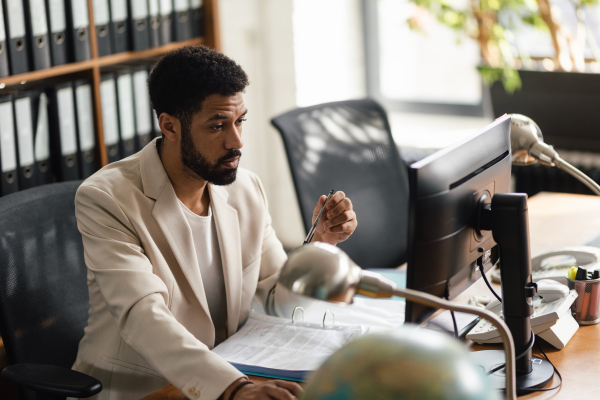 Focused young businessman in suit sitting in an office and working. Manager looking at a computer screen.