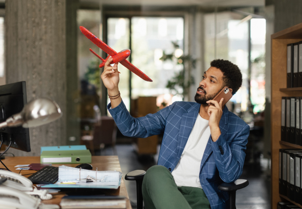 Young happy man holding model of plane in an office.