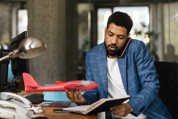 Multiracial engineer working in the office, holding model of plane.