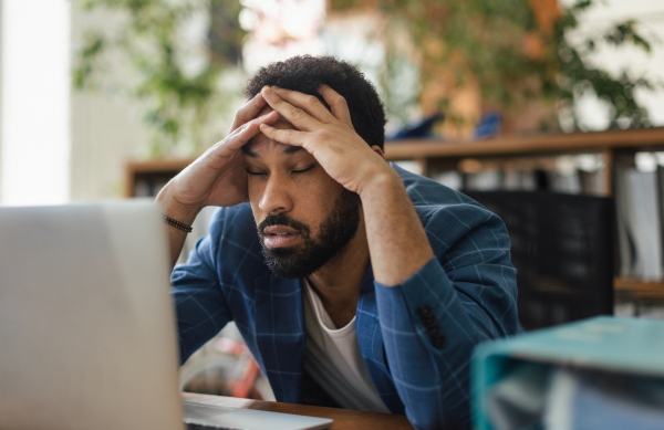 Young tired man sitting in front of laptop in his office.