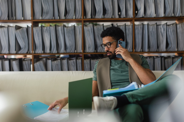 Young multiracial man sitting on a sofa and working.