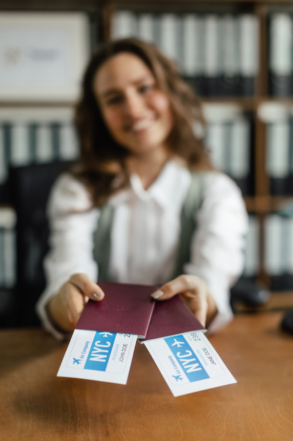 Close up of a young woman holding plane tickets.