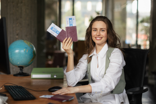 Portrait of a young woman holding plane tickets.