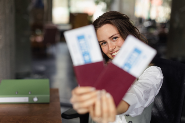 Close up of a bautiful young woman holding plane tickets.