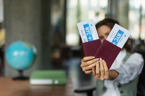 Close up of a bautiful young woman holding plane tickets.