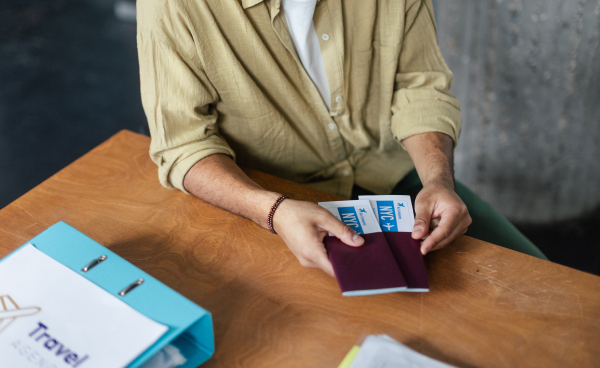 Close up of a young woman holding plane tickets.