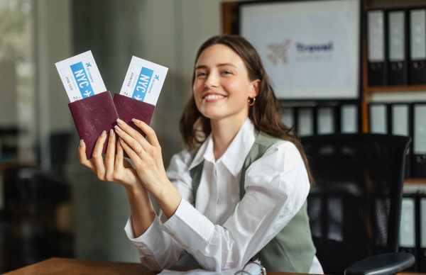 Close up of a young woman holding plane tickets.