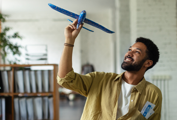 Young happy man holding model of plane in an office.