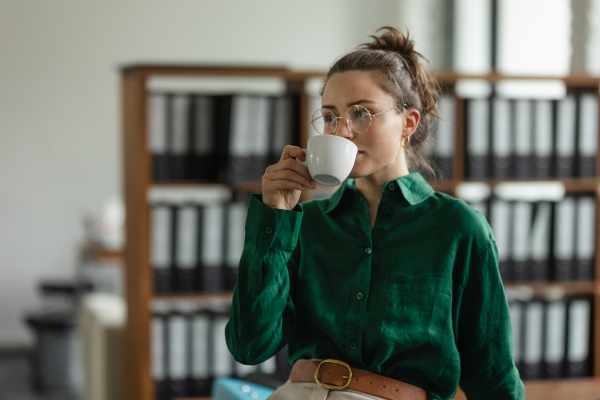 Portrait of young woman with cup of coffee in the office.