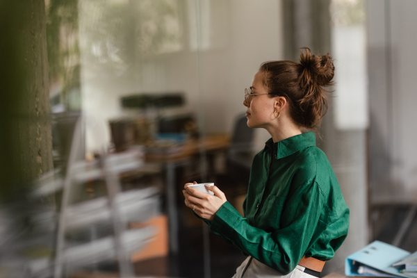 Happy female entrepreneur in her own office drinking coffee. Moment of peace after workday. Woman-owned business.