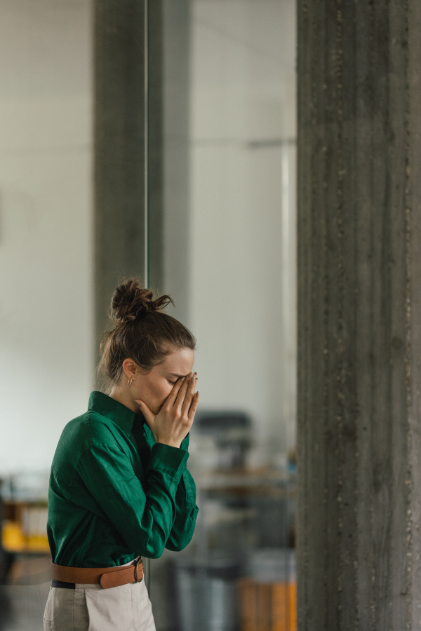 Young sad woman in office, facing a problems at work. Signs of burnout at work. Workplace issues.