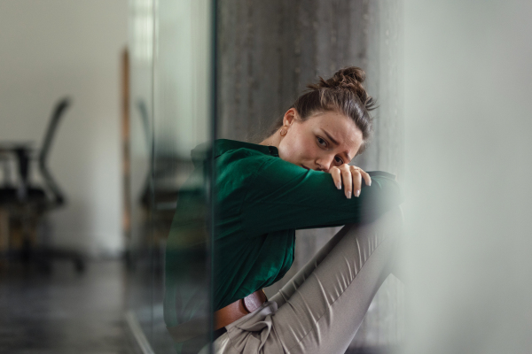 Young sad woman in office, facing a problems at work. Signs of burnout at work. Workplace issues.