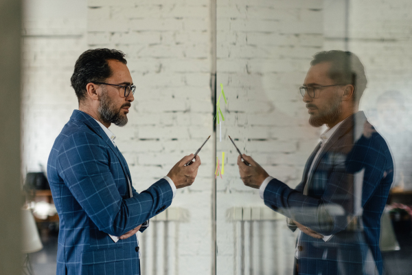 Young pensive businessman writing a notes at board in his office.