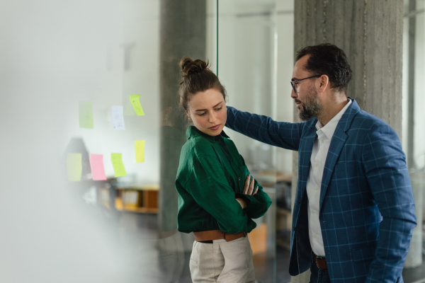 Mature man abusing his younger colleague, concept of harassment at work.