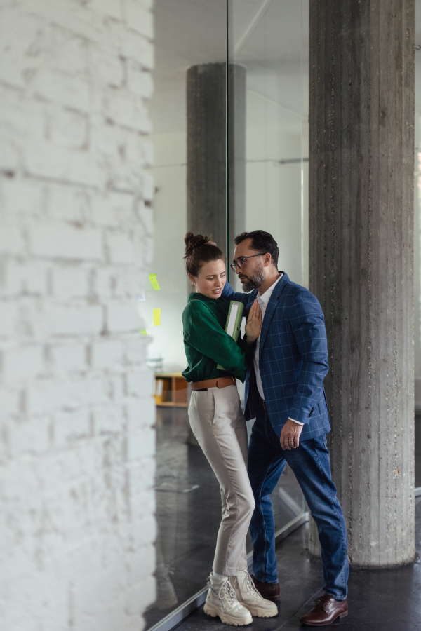 Mature man abusing his younger colleague, concept of harassment at work. Young female feeling under pressure, lacking personal space.