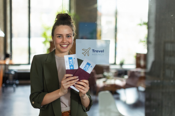 Close up of a young woman holding plane tickets.