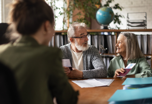 Close up of senior couple in travel agency making reservation for holiday. Eldery couple traveling in retirement.