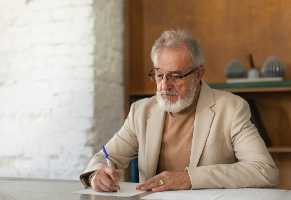 Serious eldery businessman signing document at office table. Portrait of senior man, ceo, boss signing a contract.