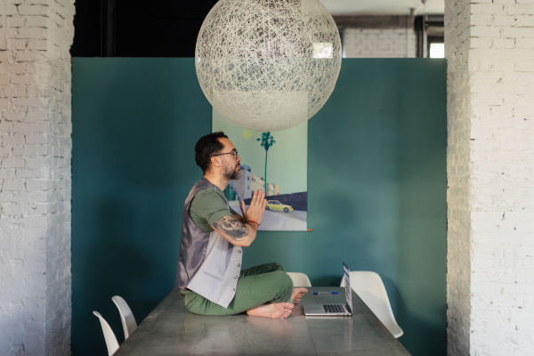 Young man sitting and meditating in the office.