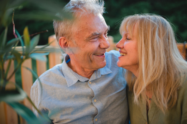 A portrait of affectionate senior couple spending time together in garden at home.