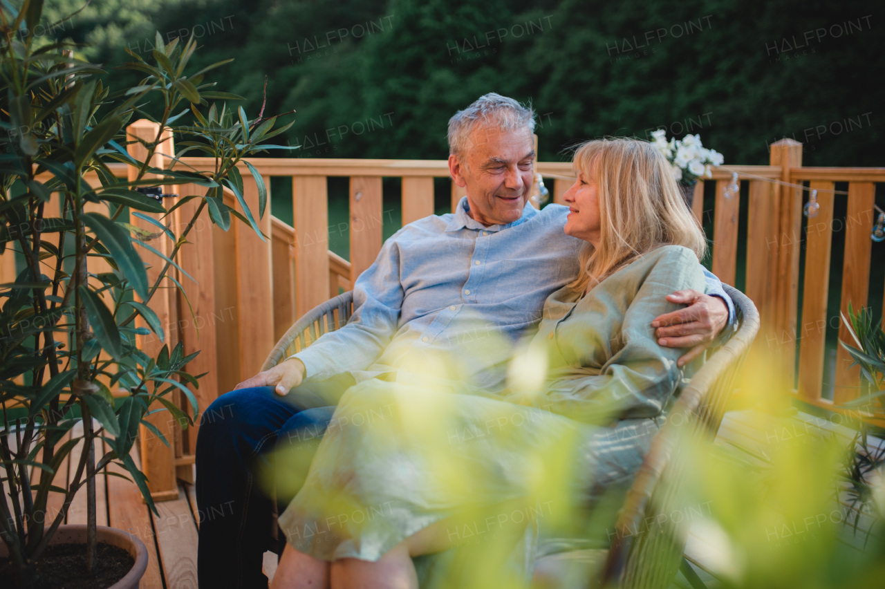 A portrait of affectionate senior couple spending time together in garden at home.