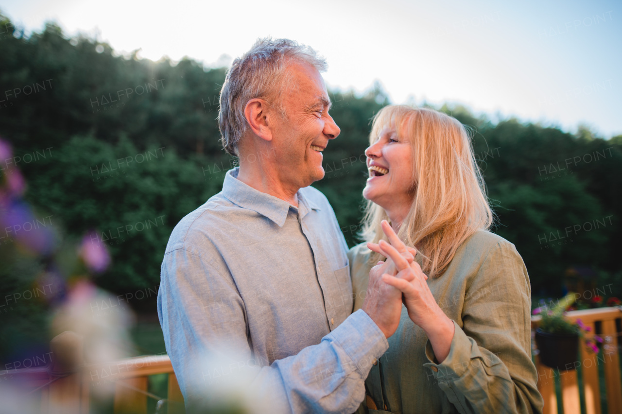 A portrait of affectionate senior couple spending time together and dancing in garden at home.