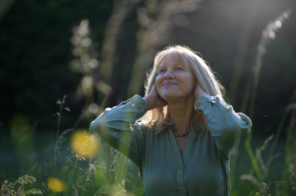 A senior woman with face up at park on summer day, mental health concept.