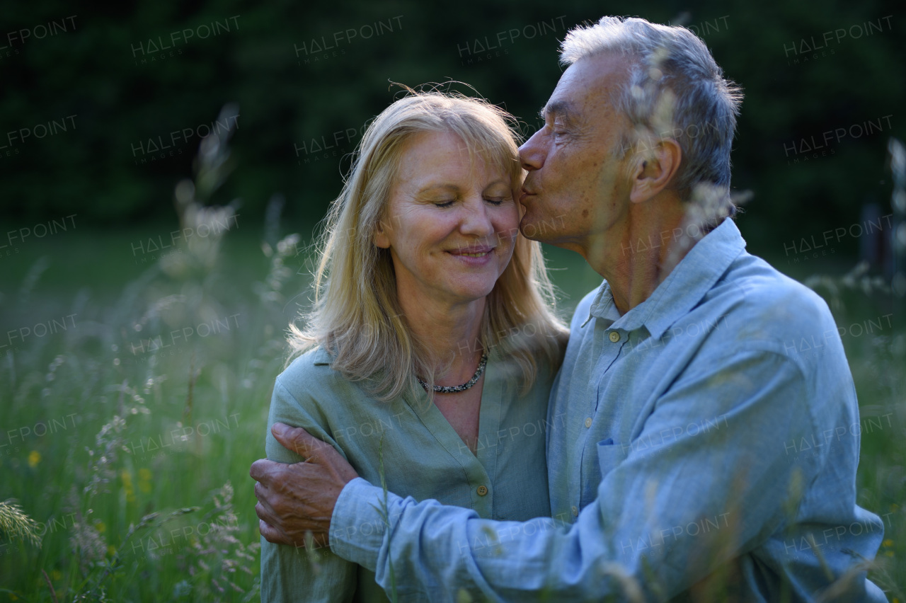 A portrait of affectionate senior couple kissing in nature.