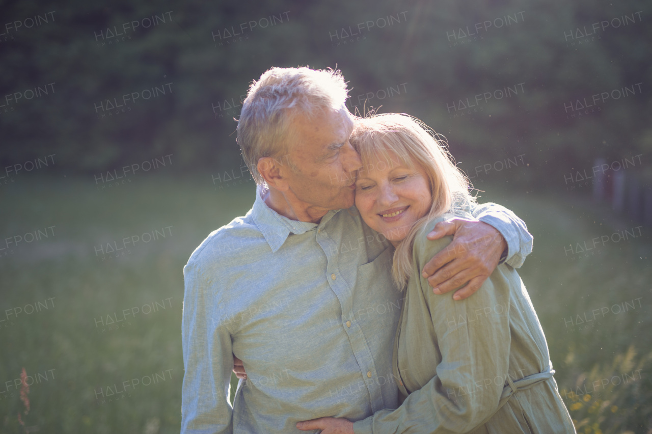 A portrait of affectionate senior couple kissing in nature.