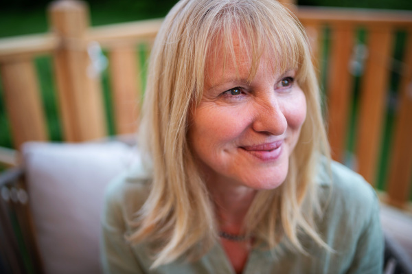 A happy mature woman relaxing on terrace in summer.