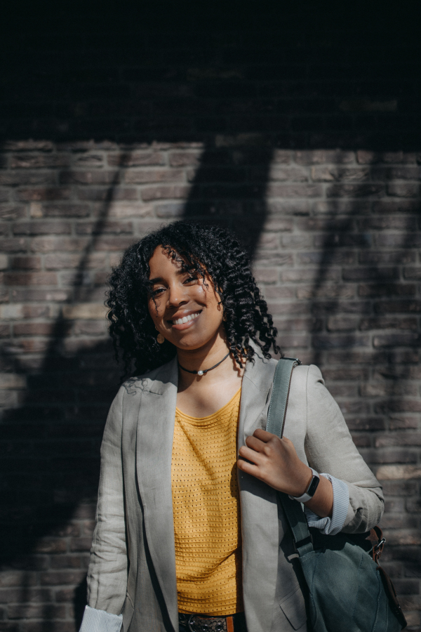 A portrait of young biracial woman wearing outdoors in street.