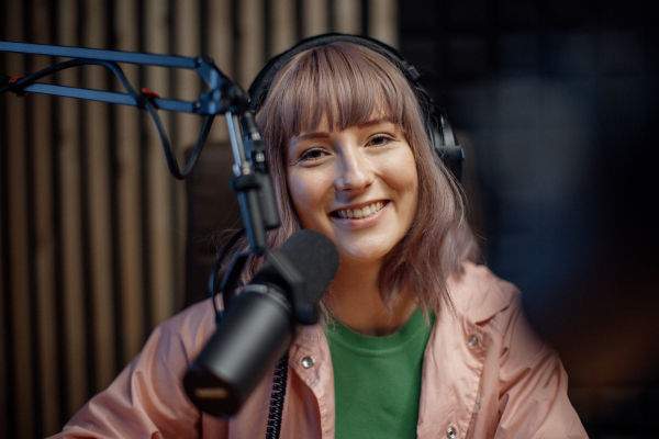 A portrait of female radio host speaking in microphone while moderating a live show