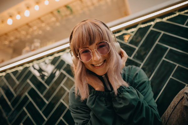 A young woman wearing headphones and enjoying listening to music indoors.