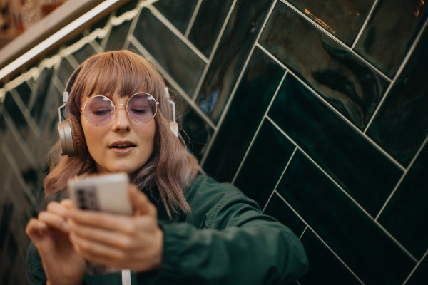 A young woman wearing headphones and enjoying listening to music indoors.