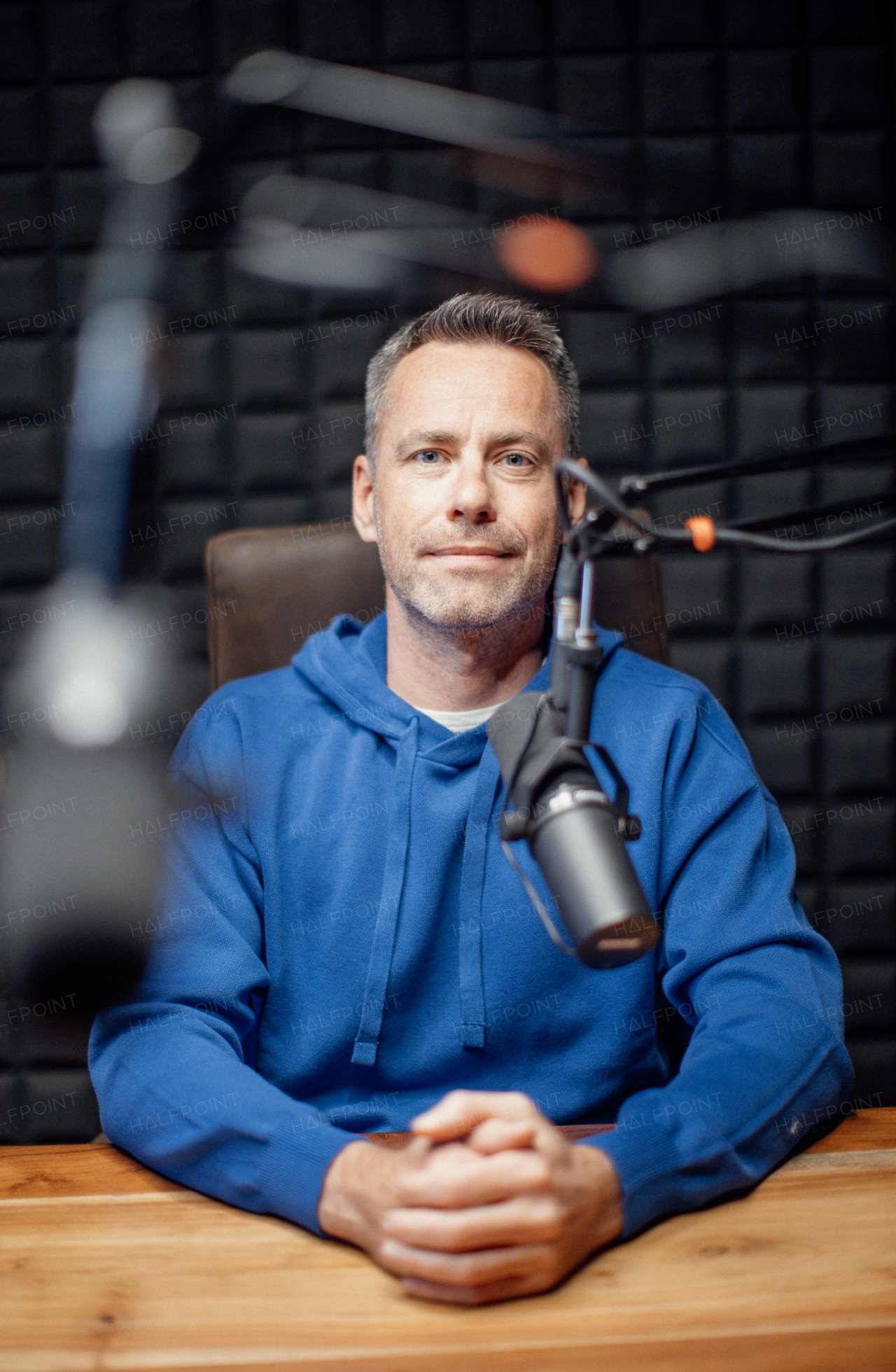 A portrait of mature radio host speaking in microphone while moderating a live show